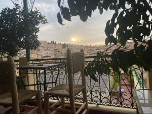 a balcony with chairs and a table and a view of the city at Riad Taj Salma in Fez