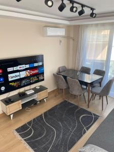 a living room with a table and chairs and a tv at Trump Tower - Cevahir Shopping Center - Şişli Metro İki yatak odalı Klimalı Tüm Daire in Istanbul