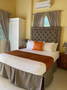 a bedroom with a large bed with orange and white pillows at Runthings Hideaway Stay Negril in Negril