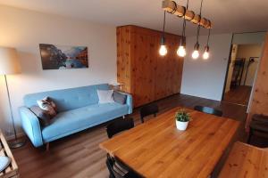 un soggiorno con un divano blu e un tavolo di legno di Stilvolle Wohnung mit traumhaftem Bergblick a Disentis