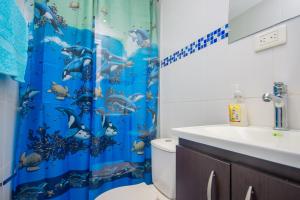 a bathroom with a toilet and a blue shower curtain at Blue Coast Hostal in Medellín +63 photos