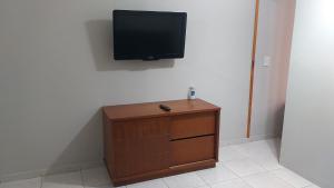 uma televisão de ecrã plano numa parede com um armário de madeira em Apartamento a 500 metros da Praia doForte em Cabo Frio