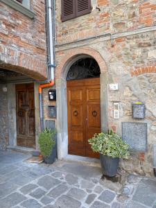 a stone building with a wooden door and two potted plants at La Casa in Castello in Ambra +37 photos