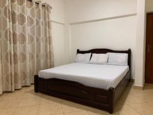 Schlafzimmer mit einem Bett mit weißer Bettwäsche und Vorhängen in der Unterkunft Two Bedroom Space Near KNUST & CCC in Kumasi