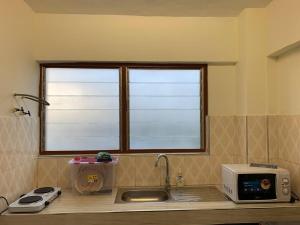 eine Küchentheke mit einer Mikrowelle und einem Fenster in der Unterkunft Two Bedroom Space Near KNUST & CCC in Kumasi