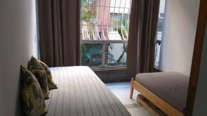 um quarto com uma cama e uma grande janela em Apartamento a 500 metros da Praia doForte em Cabo Frio