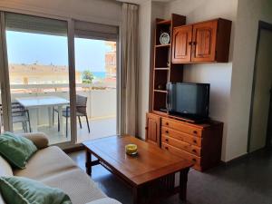 - un salon avec un canapé, une télévision et une table dans l'établissement apartamento con vistas al mar a pocos metros de la playa, à Valence