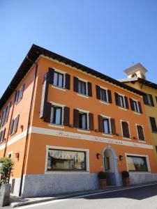 a orange building with black windows on a street at Hotel Adler in Menaggio