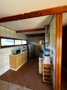una pequeña cocina con fogones y nevera. en Cabaña Curaquilla - Arauco, en Arauco