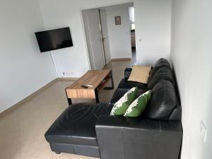 uma sala de estar com um sofá de couro preto e uma mesa em Appartement Cosy em Pavillons-sous-Bois