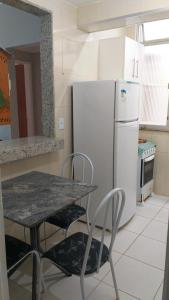 uma cozinha com uma mesa e um frigorífico branco em Apartamento a 500 metros da Praia doForte em Cabo Frio