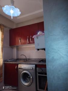 een keuken met rode kasten en een wasmachine bij Manar appart in Marrakesh