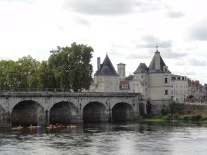 a bridge over a river with kayaks in front of a castle at Résidence Notre Dame in Châtellerault