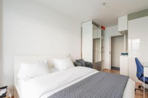 a bedroom with a large white bed and a blue chair at A 3 km du centre ville in Brussels