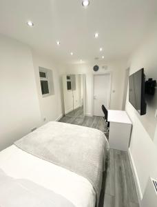 a white bedroom with a bed and a desk at London Studio in Chingford