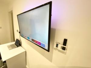 a large screen on a wall with a laptop on a desk at London Studio in Chingford