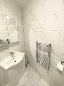 a white bathroom with a sink and a mirror at London Studio in Chingford
