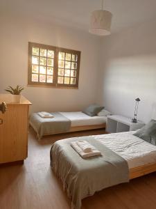1 dormitorio con 2 camas y ventana en Nina's Stay Hostel, en Charneca