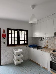 una cocina con armarios blancos y una ventana en Nina's Stay Hostel, en Charneca
