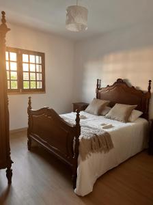 a bedroom with a large wooden bed with white sheets at Nina's Stay Hostel in Charneca