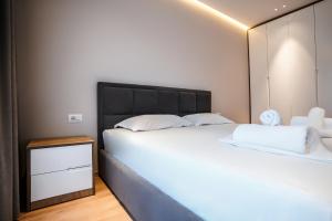 a bedroom with a large white bed and a mirror at 2BR at Café Flora - Skanderbeg Square Area in Tirana