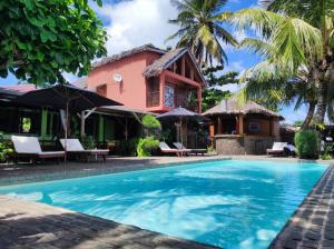 a villa with a swimming pool in front of a house at Idylle Beach in Sainte Marie
