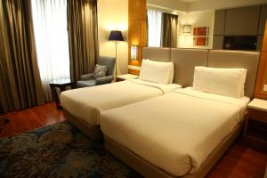 a hotel room with two beds and a chair at The Place Gurugram, a member of Radisson Individuals in Gurgaon