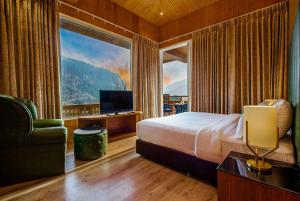 マナリにあるPalchan Hotel & Spa - A member of Radisson Individuals Retreatsのベッドと大きな窓が備わるホテルルームです。