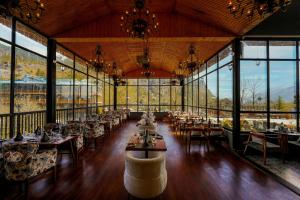 uma sala de jantar com mesas, cadeiras e janelas em Palchan Hotel & Spa - A member of Radisson Individuals Retreats em Manali