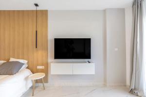 a bedroom with a tv on a white wall at Modern studio apartment with sea views 5 min from the beach in Sitio de Calahonda