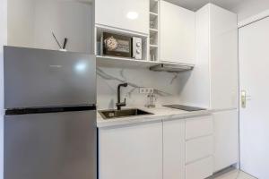 a white kitchen with a sink and a refrigerator at Modern studio apartment with sea views 5 min from the beach in Sitio de Calahonda