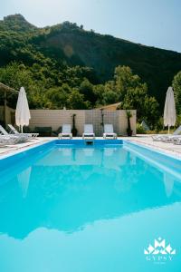 una piscina azul con 2 sillas y sombrillas en Gipsy Village Park Hotel en Asuretʼi