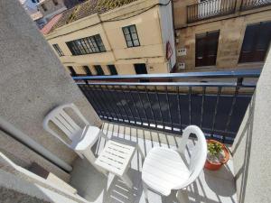 two white chairs and a plant on a balcony at Amplio Apartamento con terraza a 150 m playa in Porto do Son