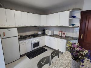 a kitchen with white cabinets and a white refrigerator at Amplio Apartamento con terraza a 150 m playa in Porto do Son