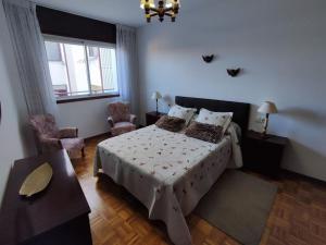 a bedroom with a bed and a table and a window at Amplio Apartamento con terraza a 150 m playa in Porto do Son
