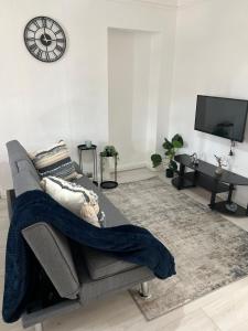 a living room with a couch and a clock on the wall at 2 bedroom with garden- Wembley in Preston