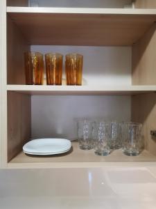 a row of glasses and a plate on a shelf at Apartment Lora in Burgas