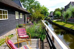 羊角村的住宿－De Galeriet Giethoorn，两把椅子坐在河边的门廊上