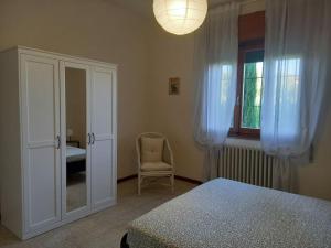 Un dormitorio con una cama y una silla y una ventana. en Casa Clelia, en Ponte Buggianese