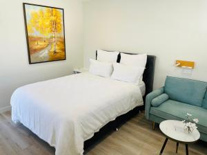 um quarto com uma cama branca e um sofá azul em 66 Express luxury apartment in New Market Our apartments has Self-checkin System em Auckland