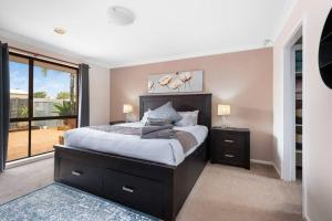 a bedroom with a large bed and a large window at Spacious 3BR house with a cosy log fire & luxury spa bath in Kalgoorlie