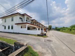 une maison blanche sur le côté d'une route dans l'établissement Air-home M1 Simpang near Aulong Econsave, 4BR, 10pax, Netflix, à Simpang