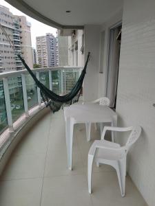un balcón con hamaca y 2 mesas y sillas en Apartamento Completo no Jardim da Barra - Barra Olímpica, en Río de Janeiro