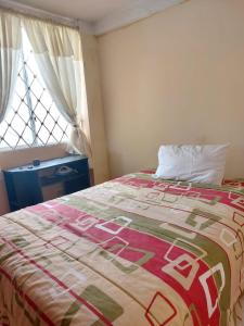 um quarto com uma cama com um edredão e uma janela em Acogedor departamento em Loja