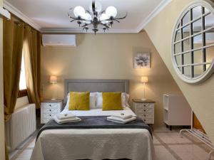 Un dormitorio con una cama con almohadas amarillas y una lámpara de araña. en Casa de Huéspedes Vecinodecerbantes, en Alcalá de Henares