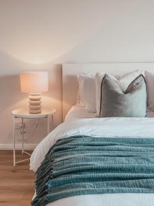 a bed with a lamp on a side table at Harrington Guest Suite in Harrington