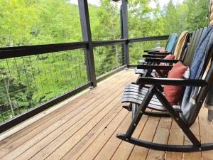 a rocking chair on a deck with a view of trees at Whispering Pines - Indoor Pool, Hot Tub, Fire Pit in Sevierville