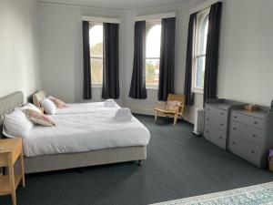 sypialnia z łóżkiem, komodą i oknami w obiekcie College Lawn Hotel w Melbourne