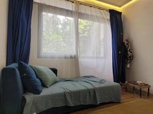 een slaapkamer met een bed en een raam met blauwe gordijnen bij Tepas Paviliun in Bandung
