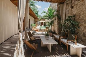 an outdoor patio with chairs and tables and a table at Ya'ax Hotel Boutique in Mérida